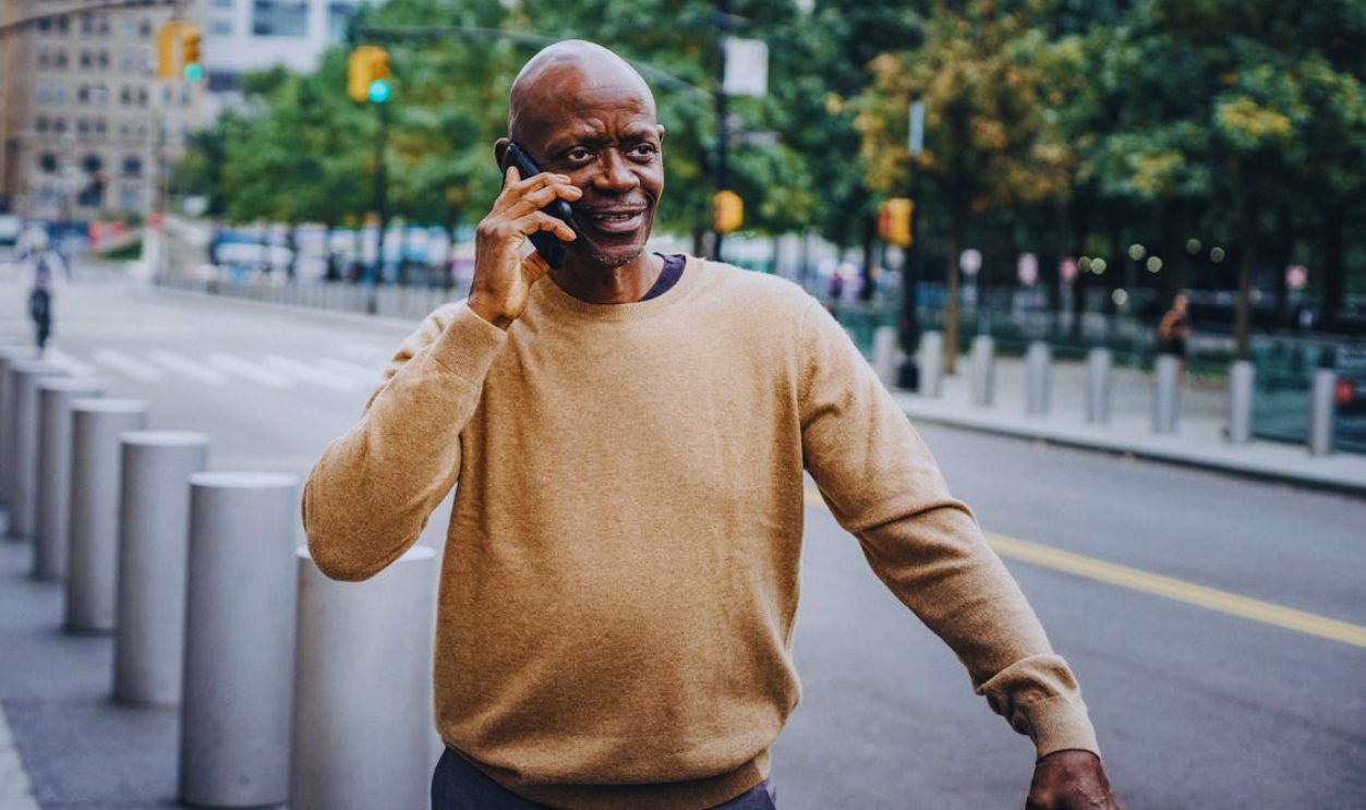 Black man speaking on phone near road