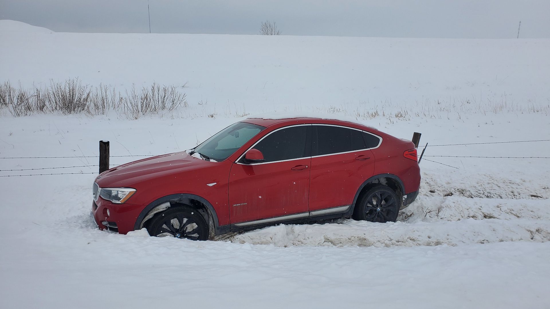 A red BMW vehicle that had slid off the road and became stranded in the snow