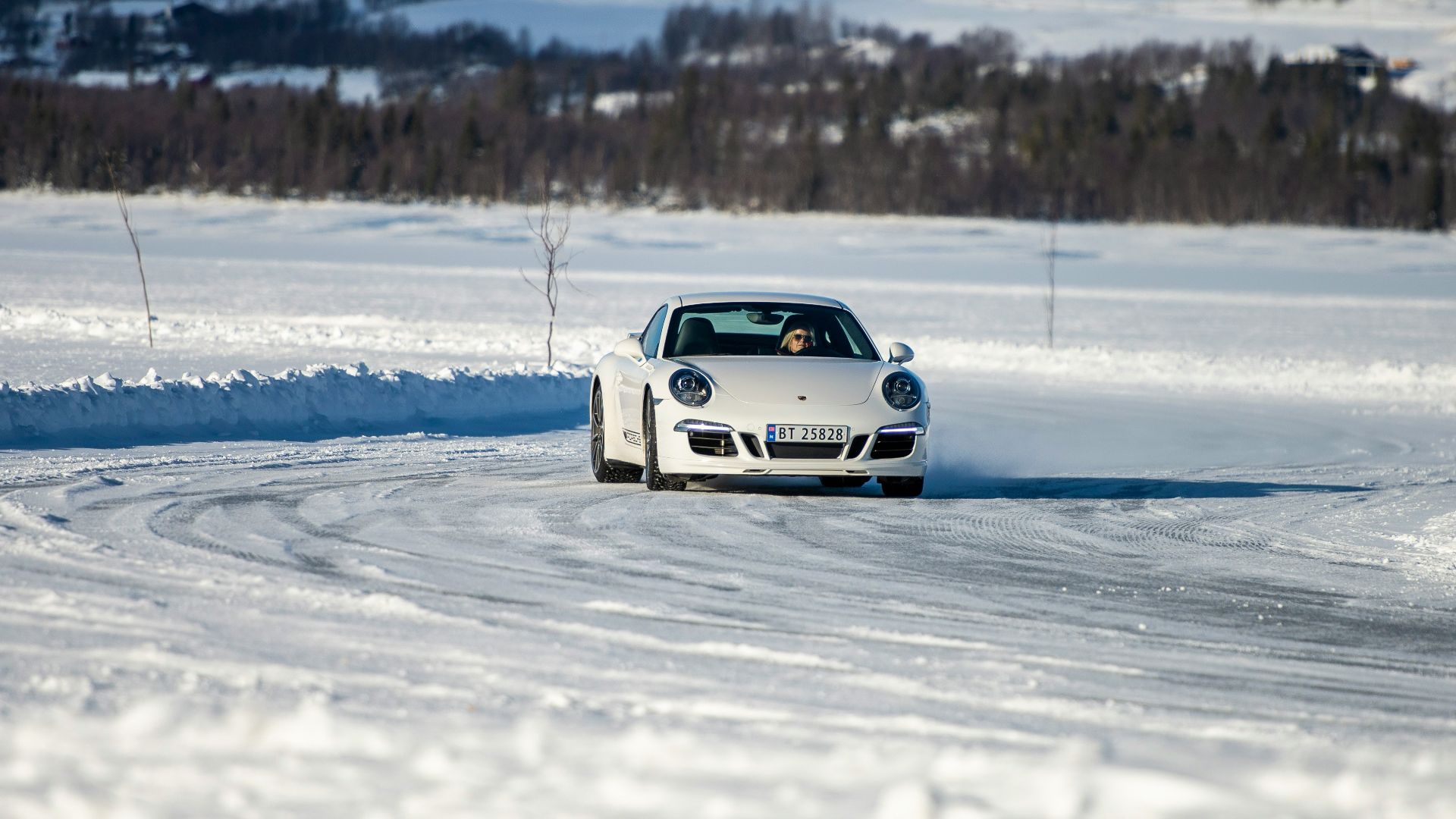 a white car driving down a snow covered road