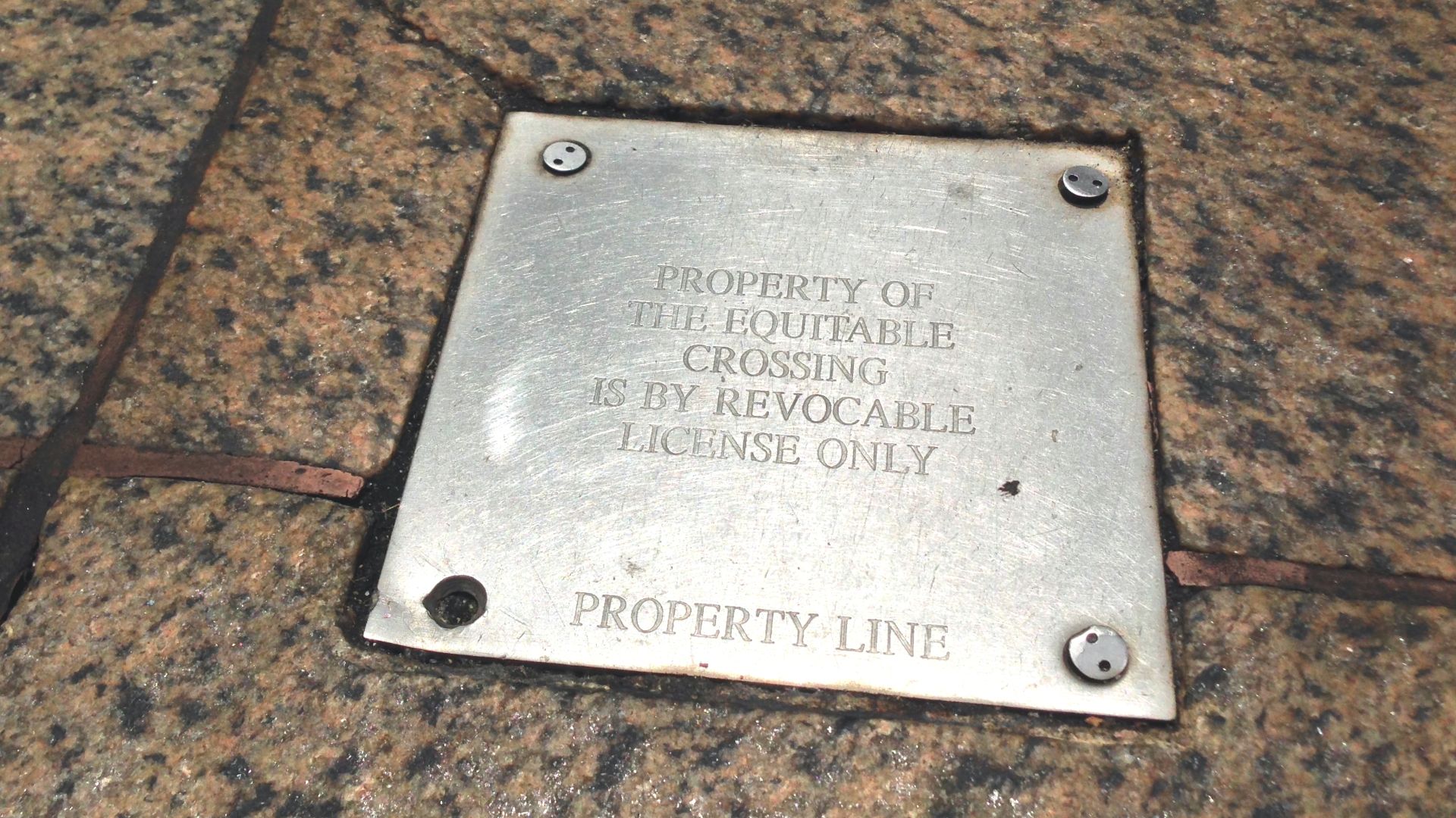 A private property line plaque embedded in the New York City sidewalk that reads,