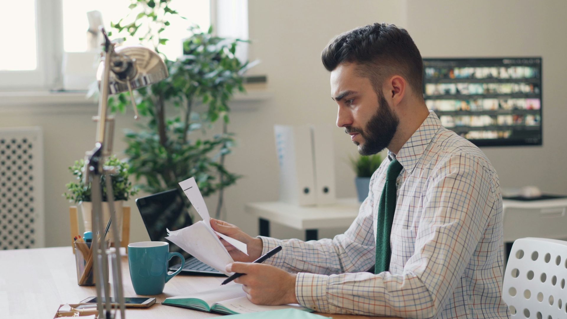 a man sitting at a desk with a laptop and papers