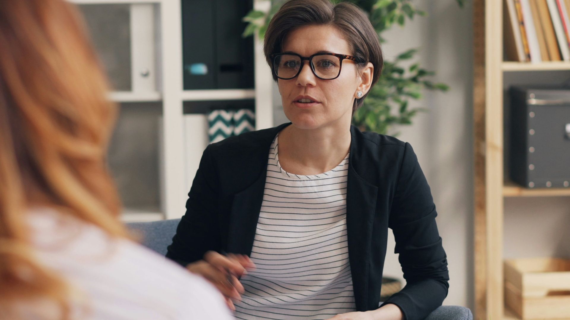 a woman sitting on a couch talking to another woman