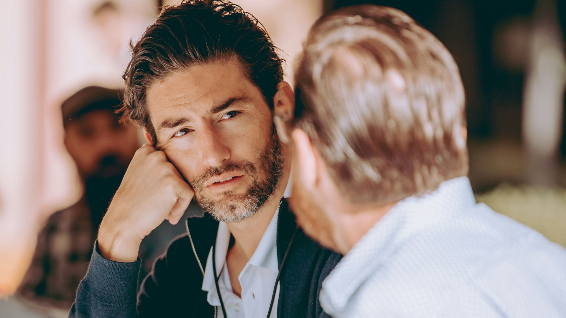two men sitting at a table talking to each other