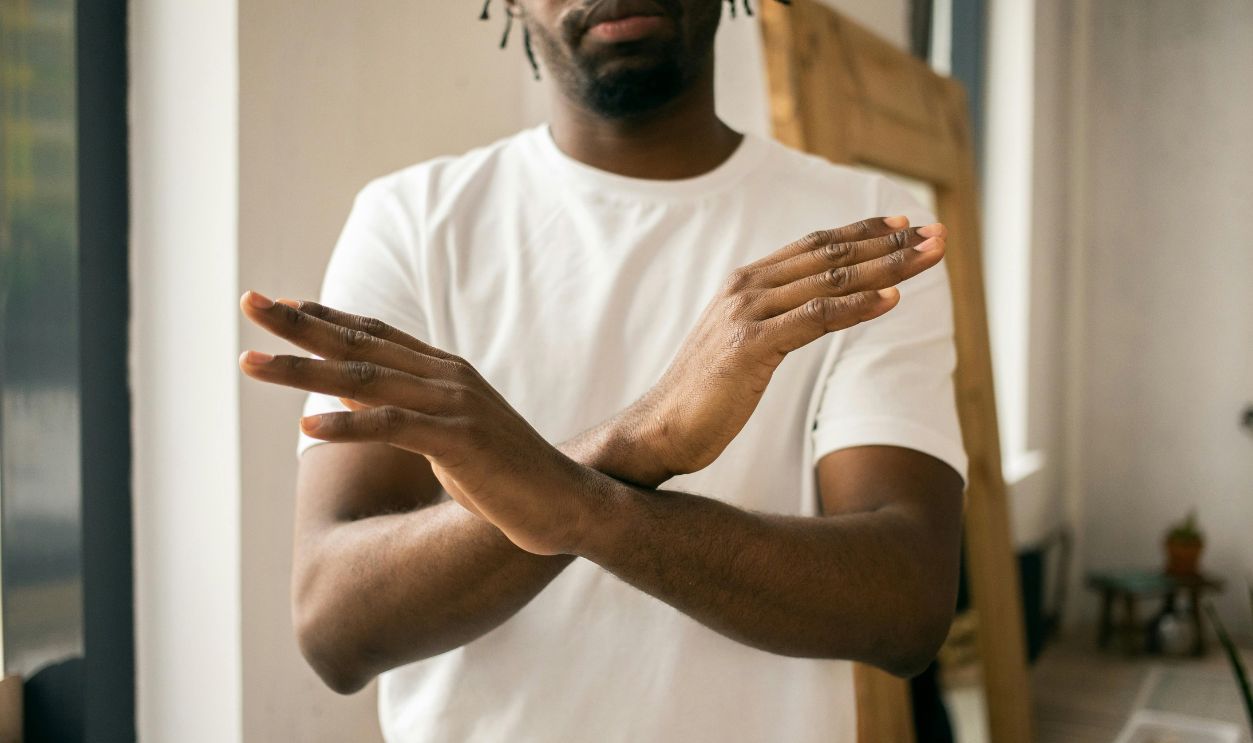 Faceless black man showing stop gesture with crossed hands