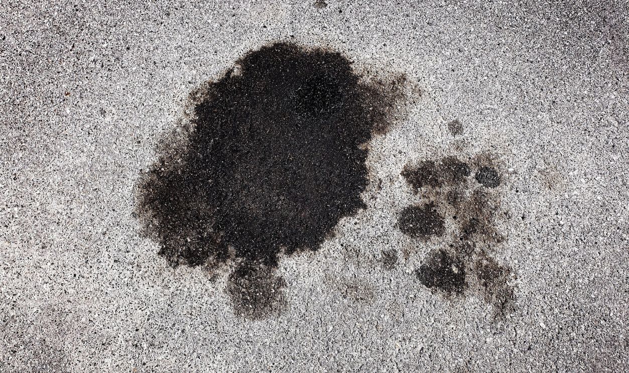 Shutterstock - 2656251657 - Oil spill spilled from car on roadway parking area