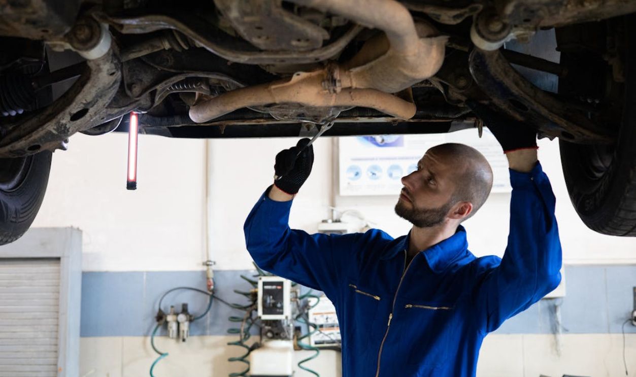Man in Blue Coverall Fixing a Vehicle