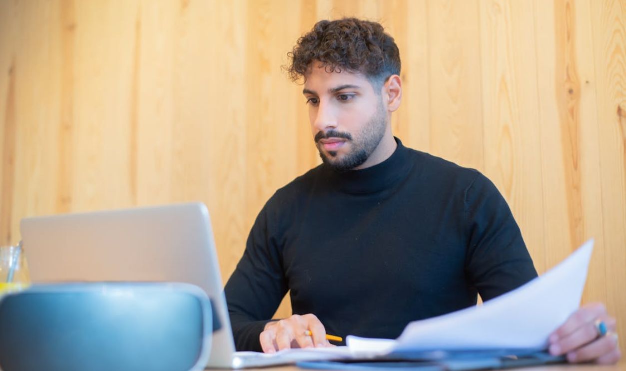 A Man Working with Documents Using a Laptop