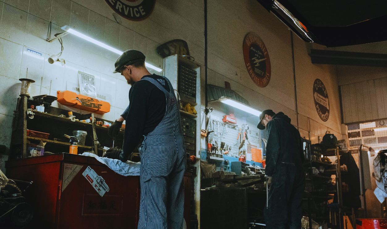 Man in Black Shirt and Blue Denim Jeans Standing Near White Wall