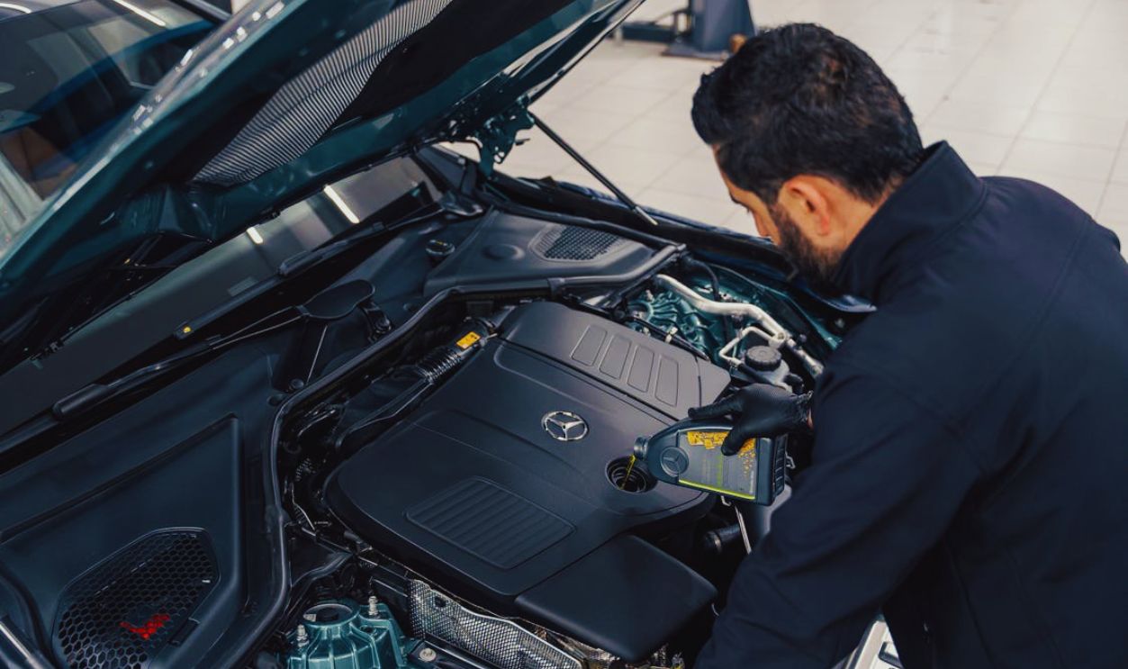 Mechanic Checking Car Engine Oil Level in Service Center