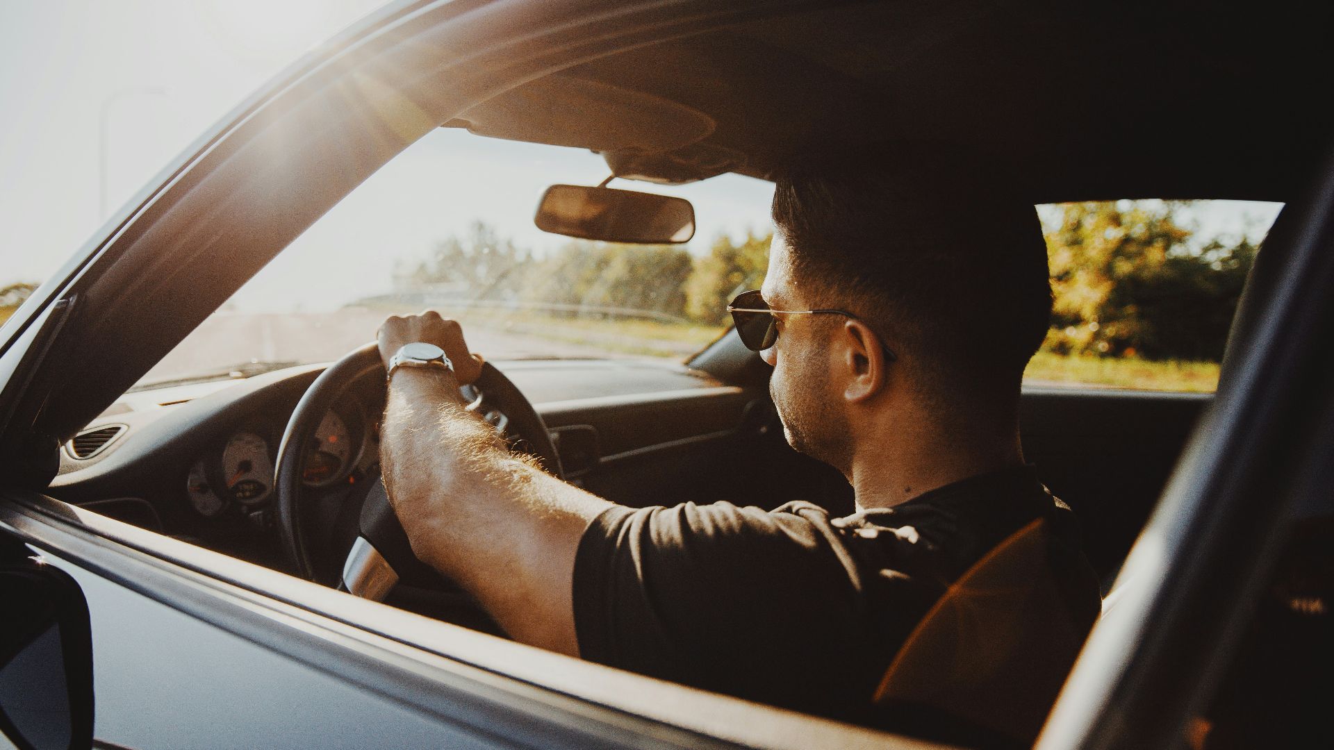 man in black jacket driving car during daytime