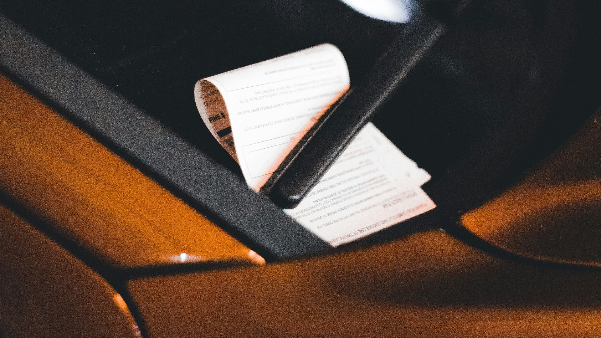 Close-up of a parking ticket on a car windshield at night, highlighting urban parking issues.