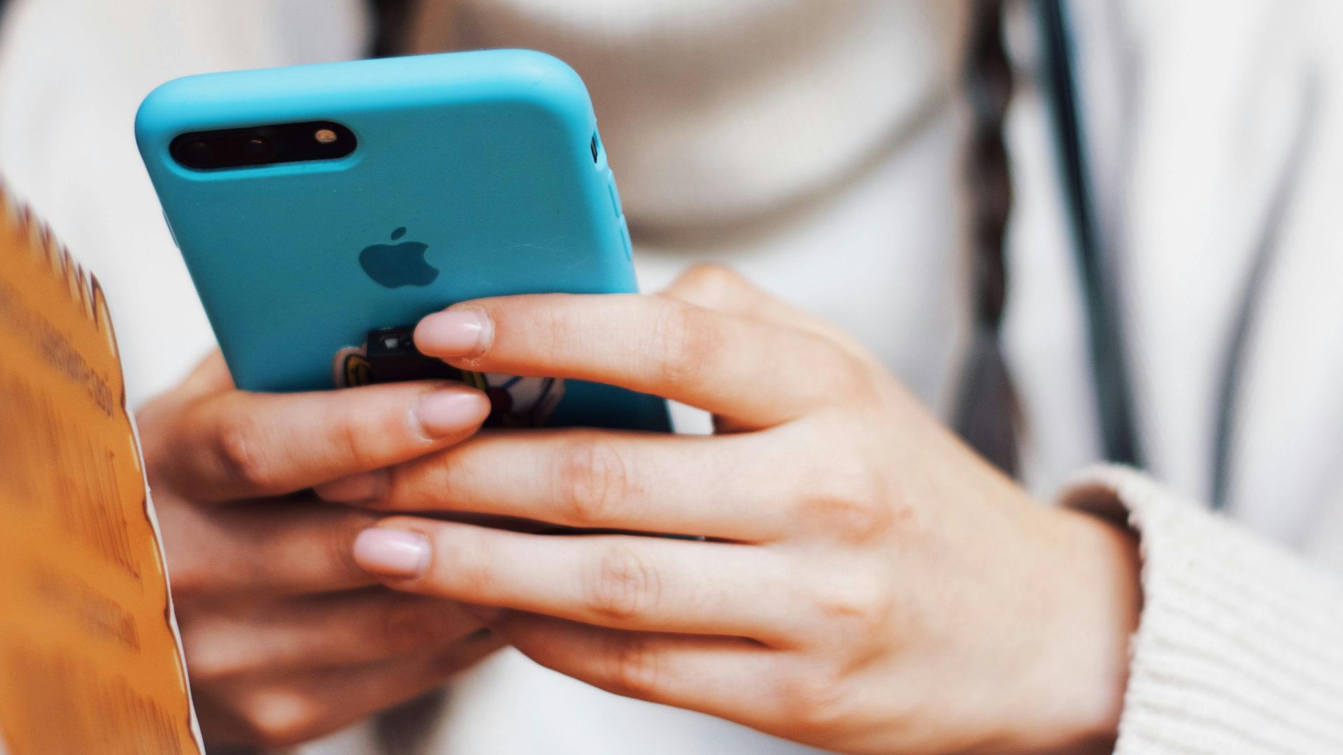 A person texting on a smartphone with a blue case indoors.
