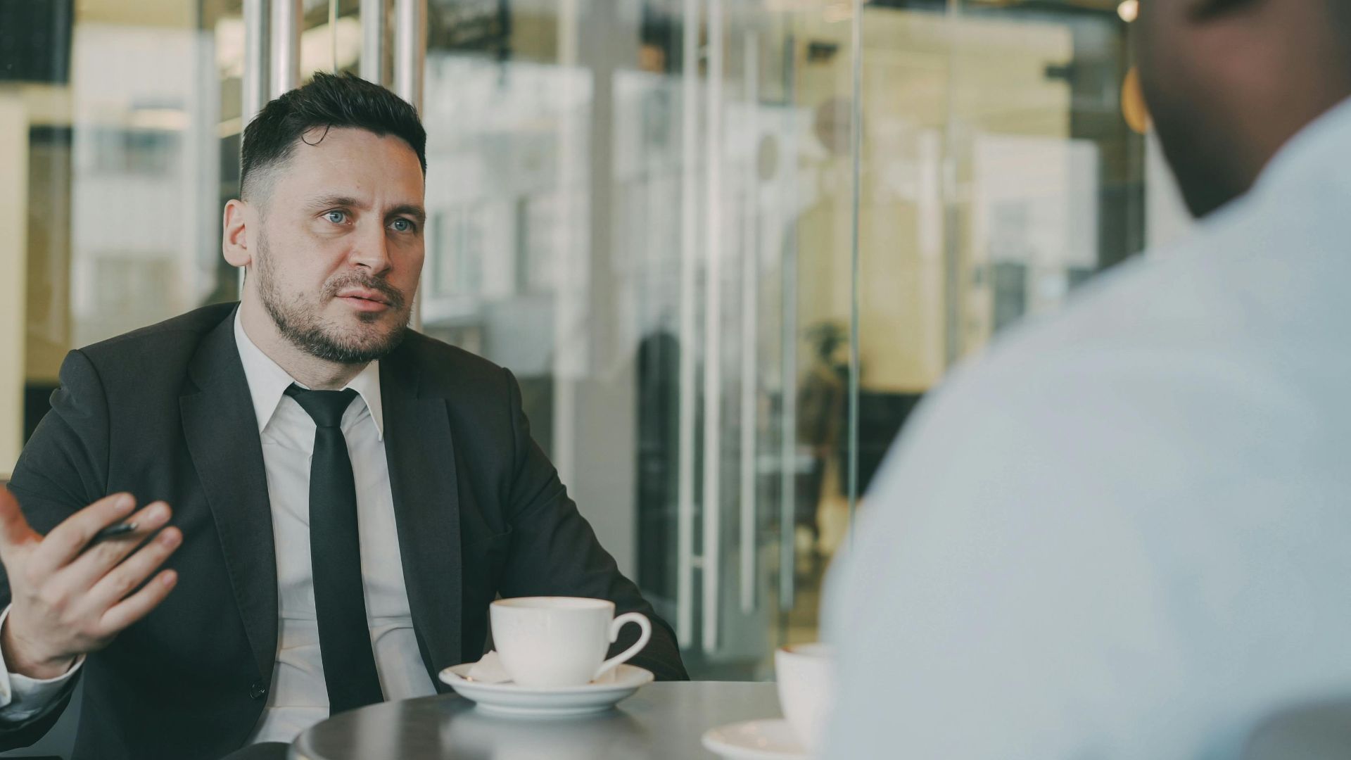 Two businessmen having a professional discussion over coffee in a modern cafe setting.