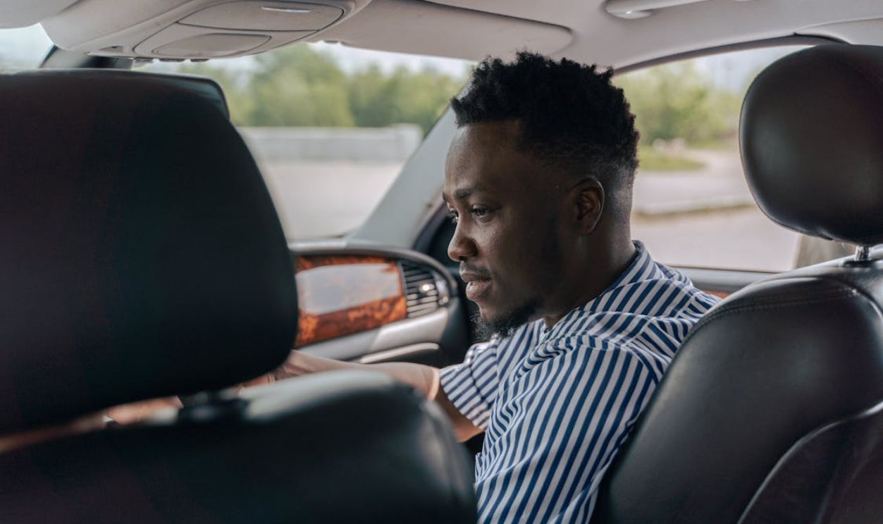 Man in White and Blue Striped Dress Shirt Driving Car