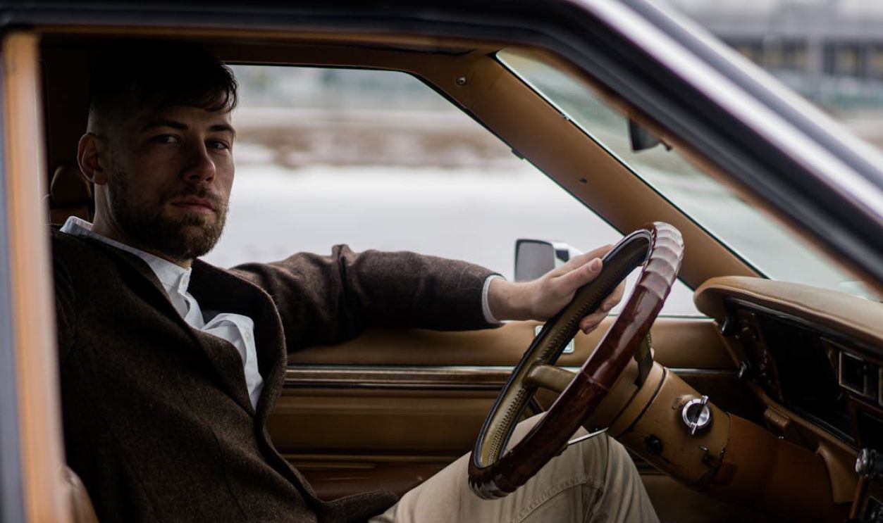 Guy sitting in car with hand on steering wheel