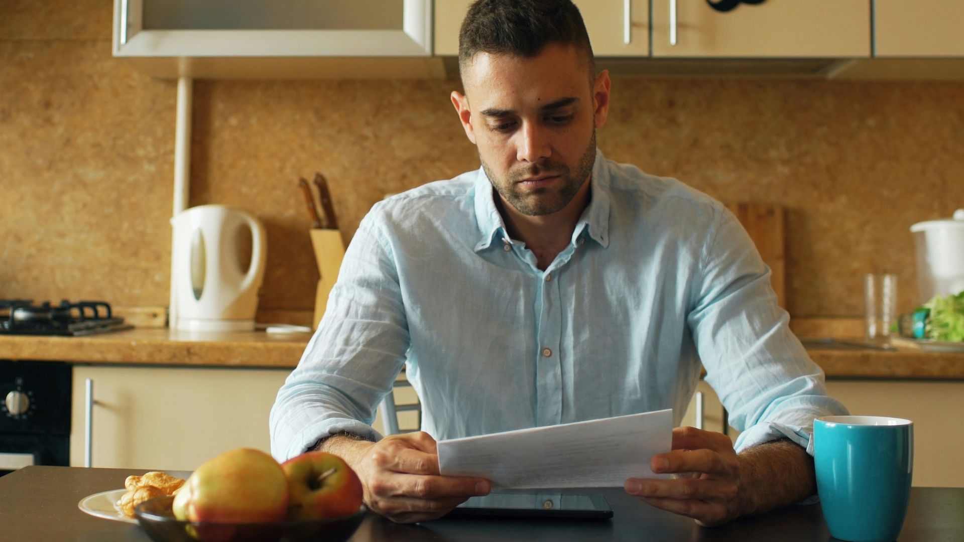 Man reading document at kitchen table with coffee