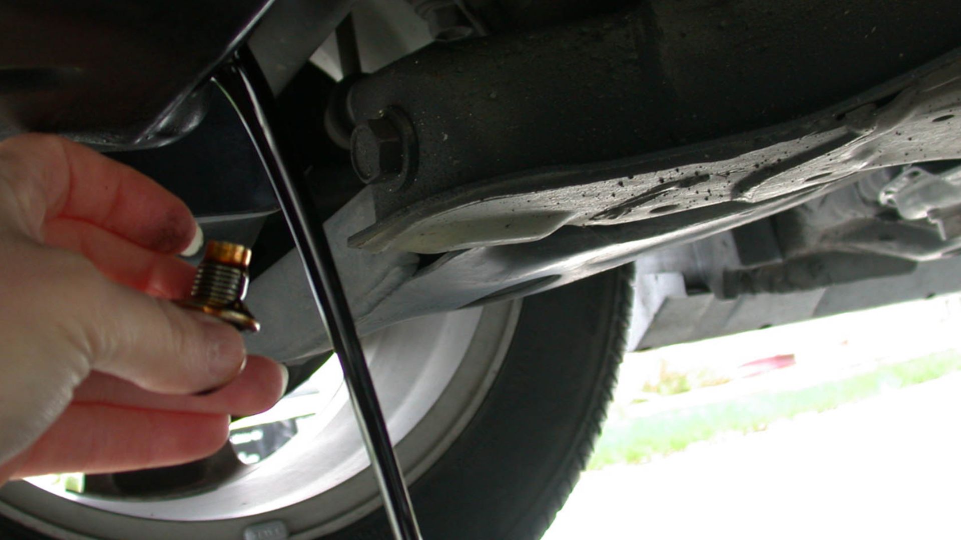 Draining the motor oil out of an automobile as part of an oil change.