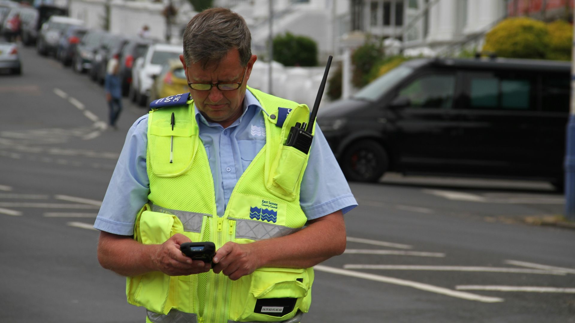 a man in a yellow vest looking at a cell phone