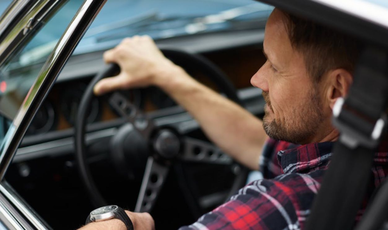 Bearded man in plaid shirt in car