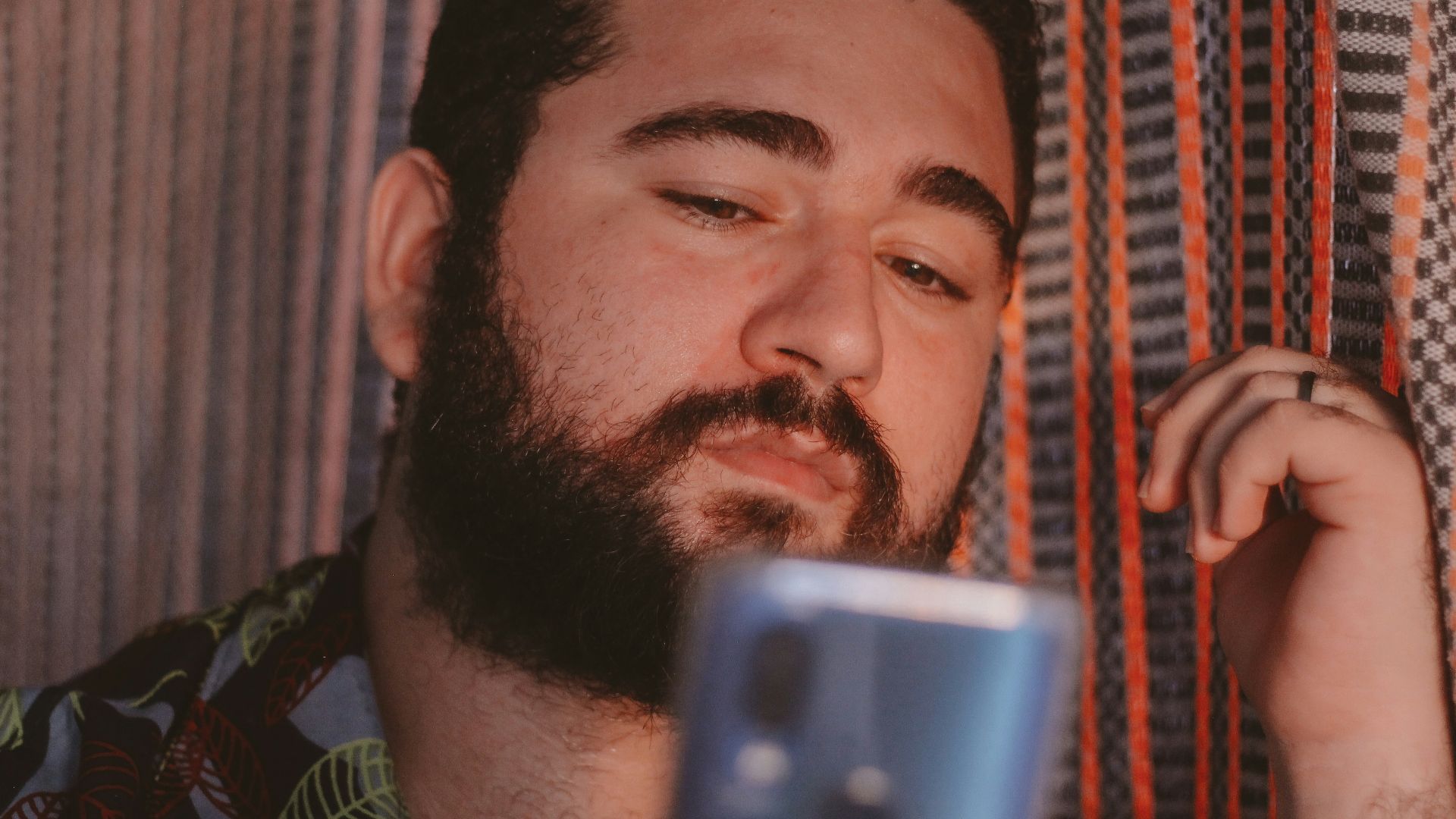 man in green and black camouflage shirt holding blue smartphone
