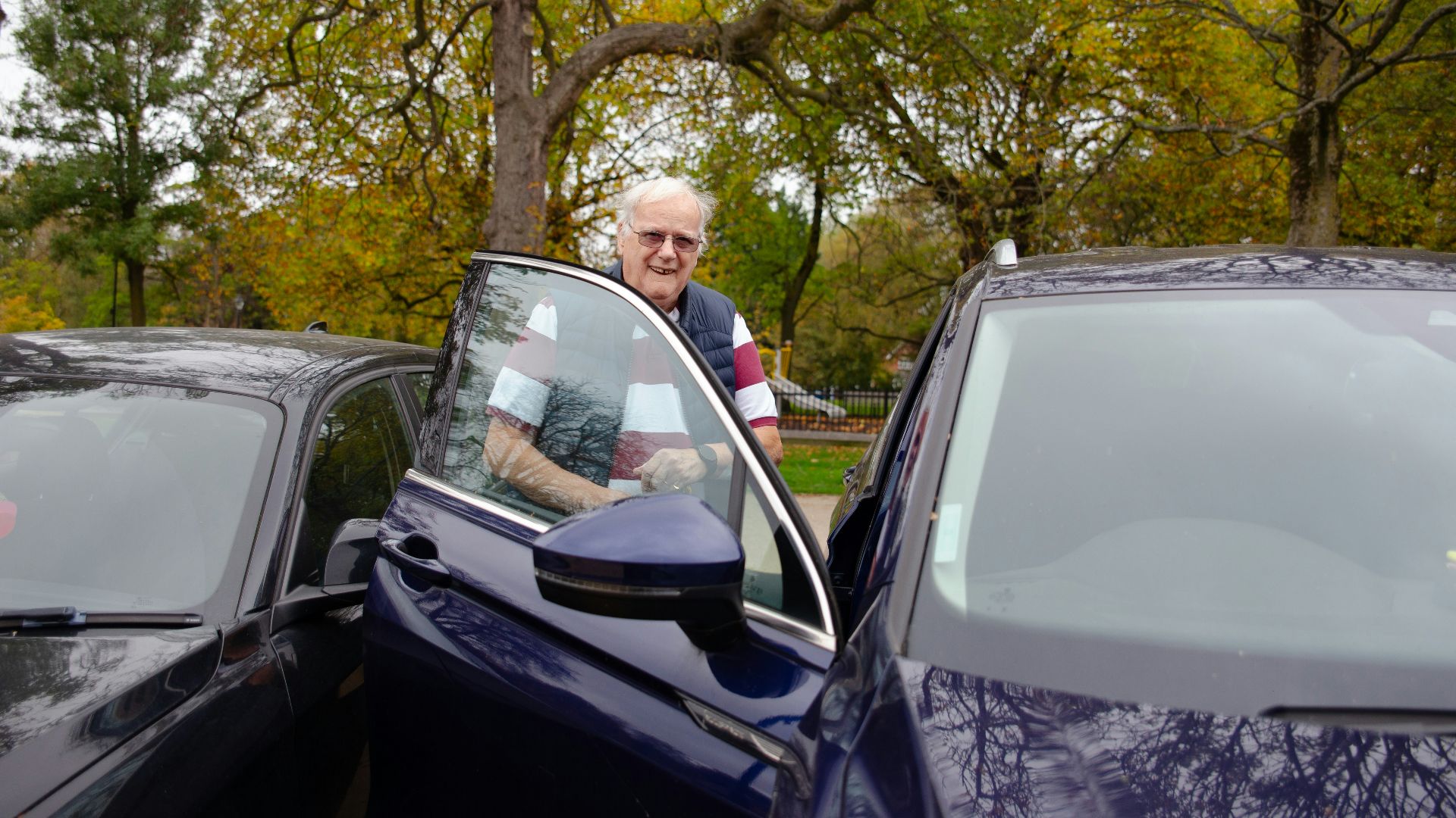 Elderly man standing by an open car door.