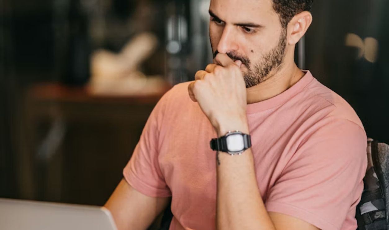 a man sitting at a table with a laptop and a cup
