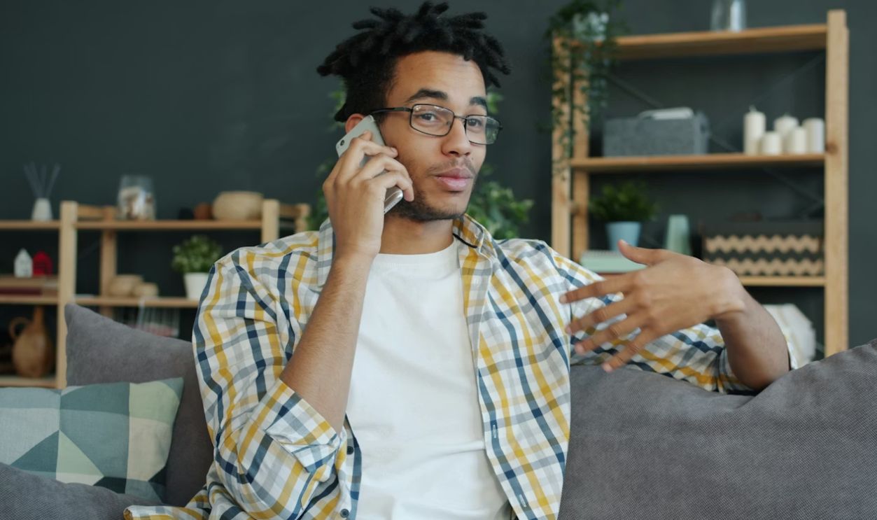Young man talking on a cell phone while sitting.