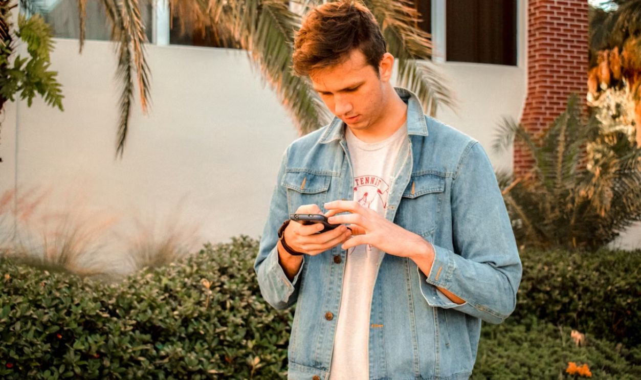 man in blue denim jacket using phone