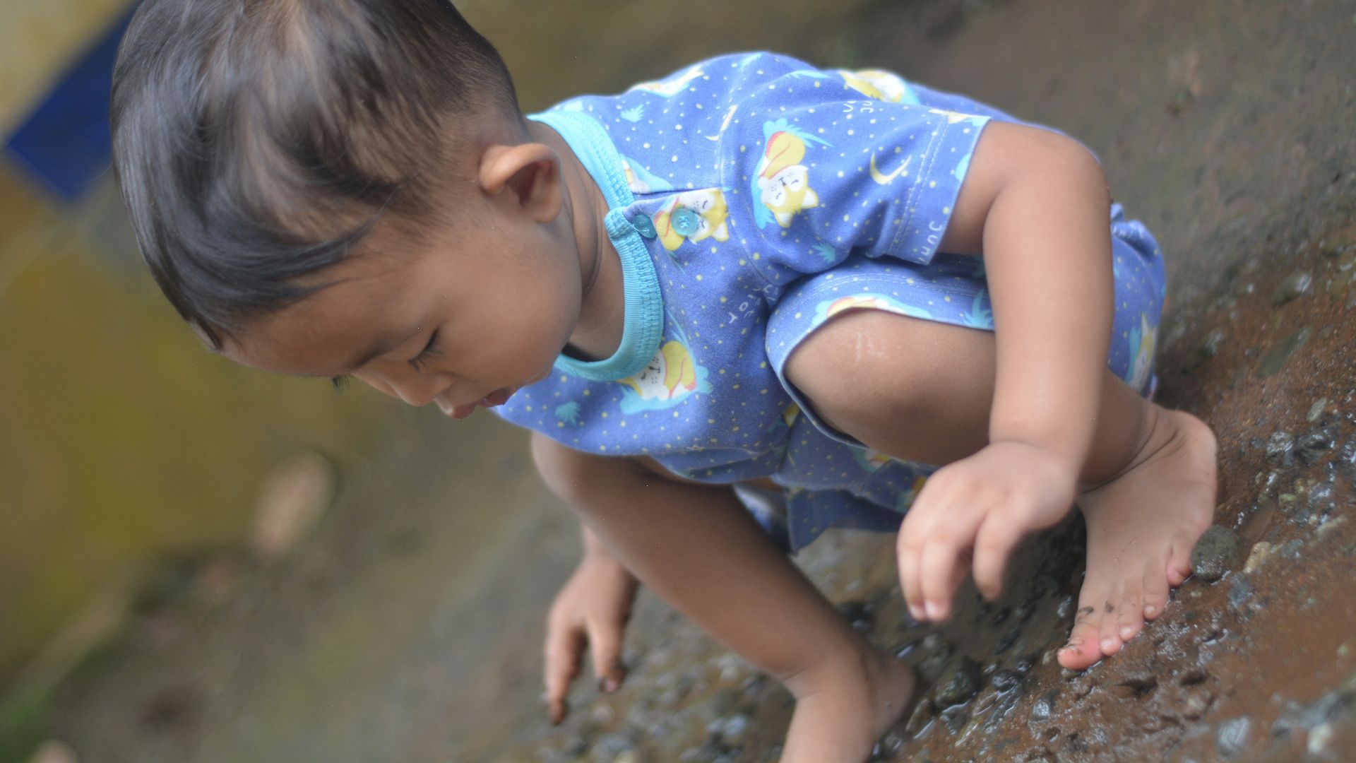 Young child playing with water and stones