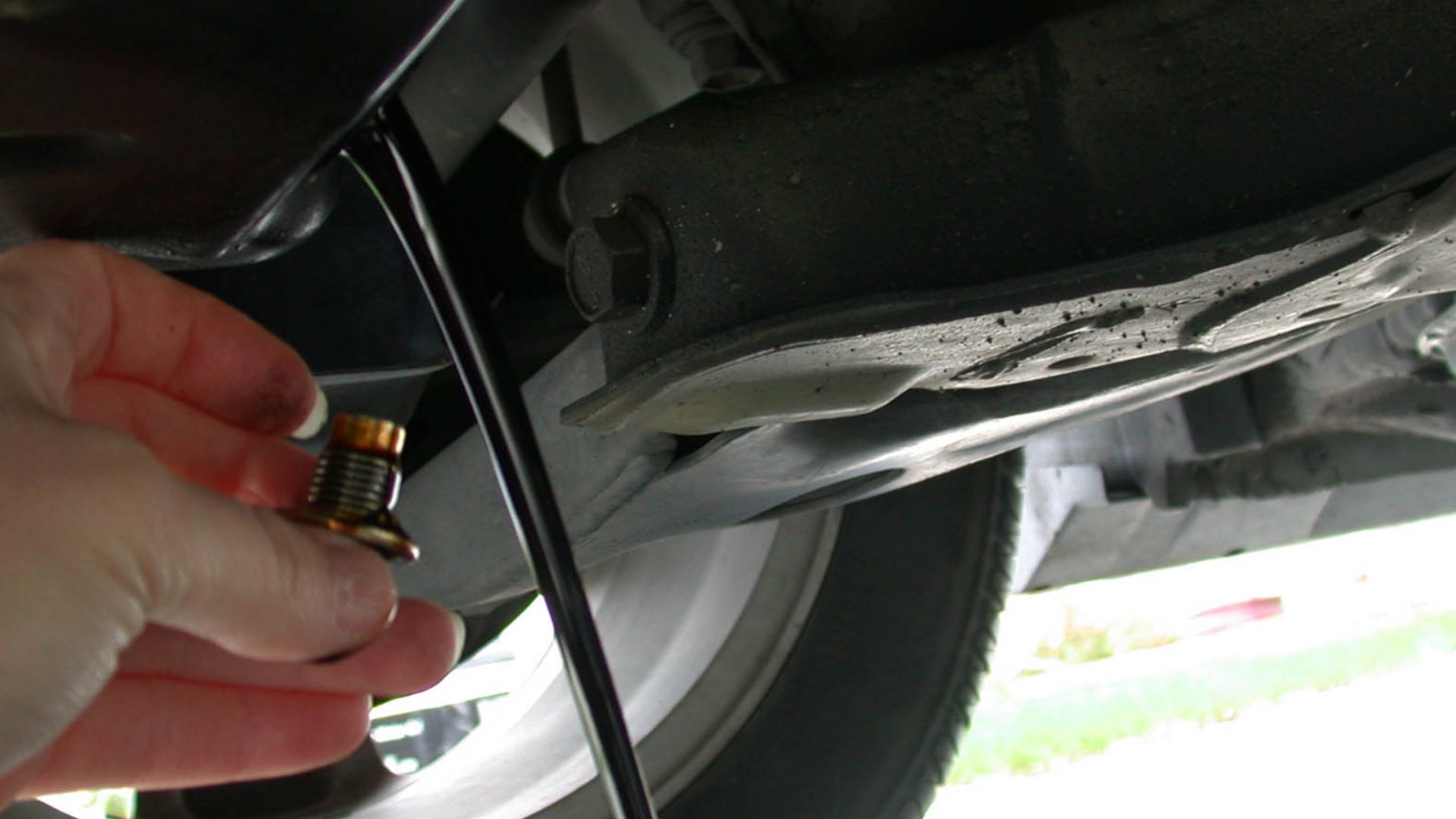 Draining the motor oil out of an automobile as part of an oil change.