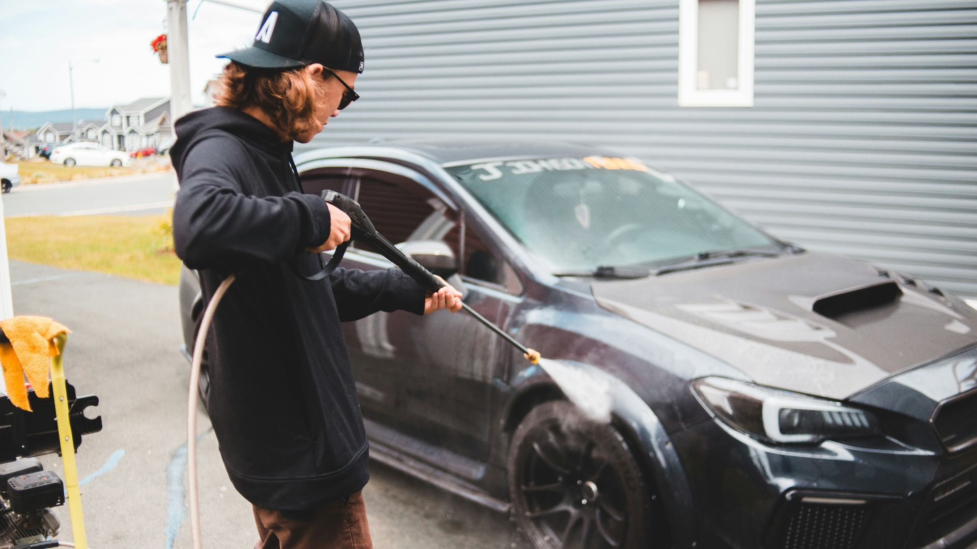 man in black jacket and brown pants standing beside black car during daytime