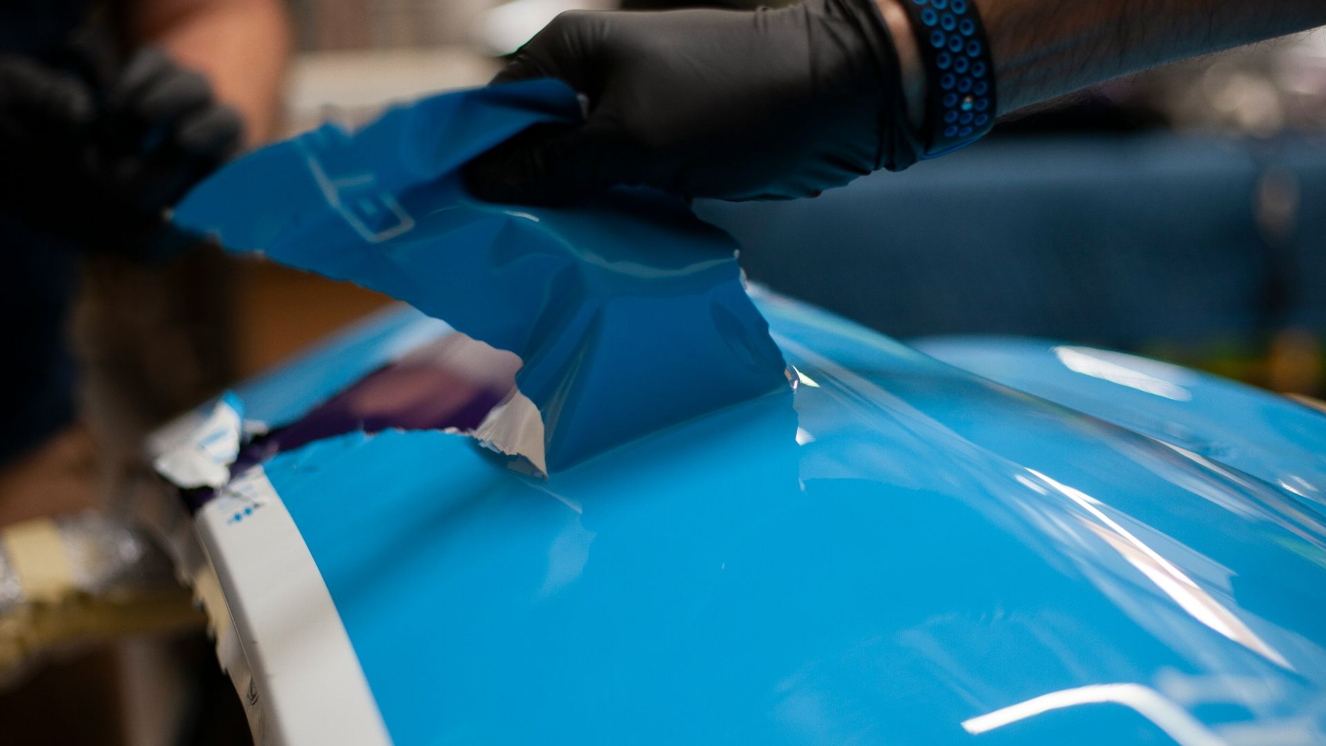 a person wearing gloves and gloves is painting a blue car