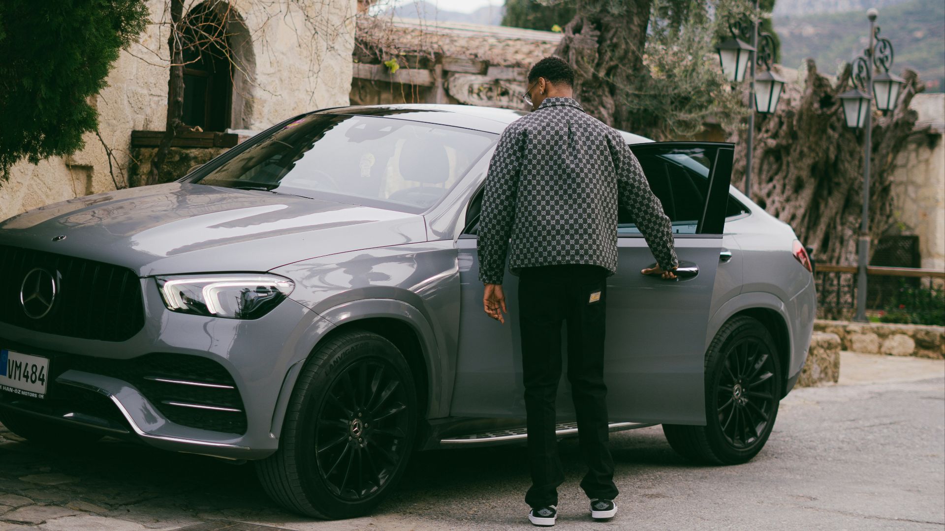 Man opening the door of a grey mercedes suv.