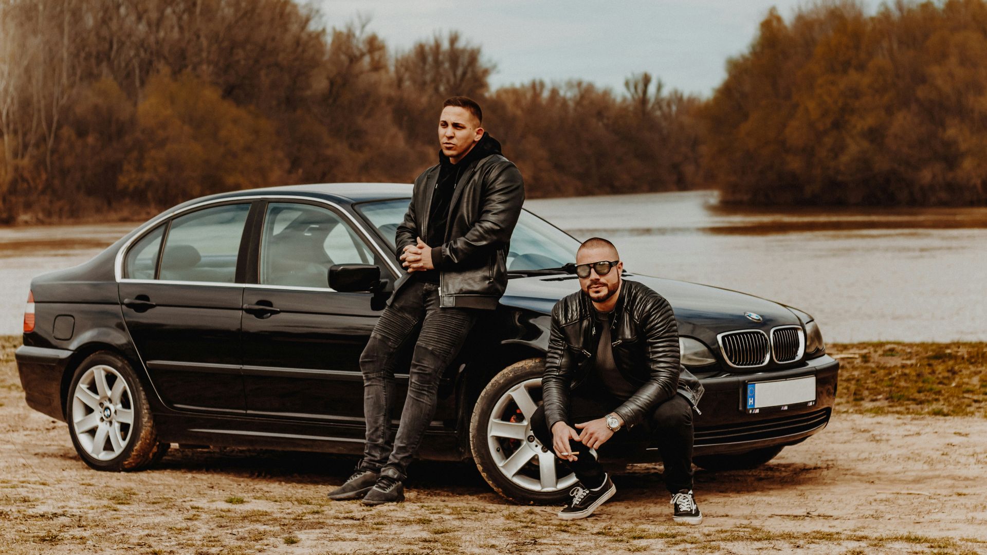 man in black jacket and black pants sitting on black car