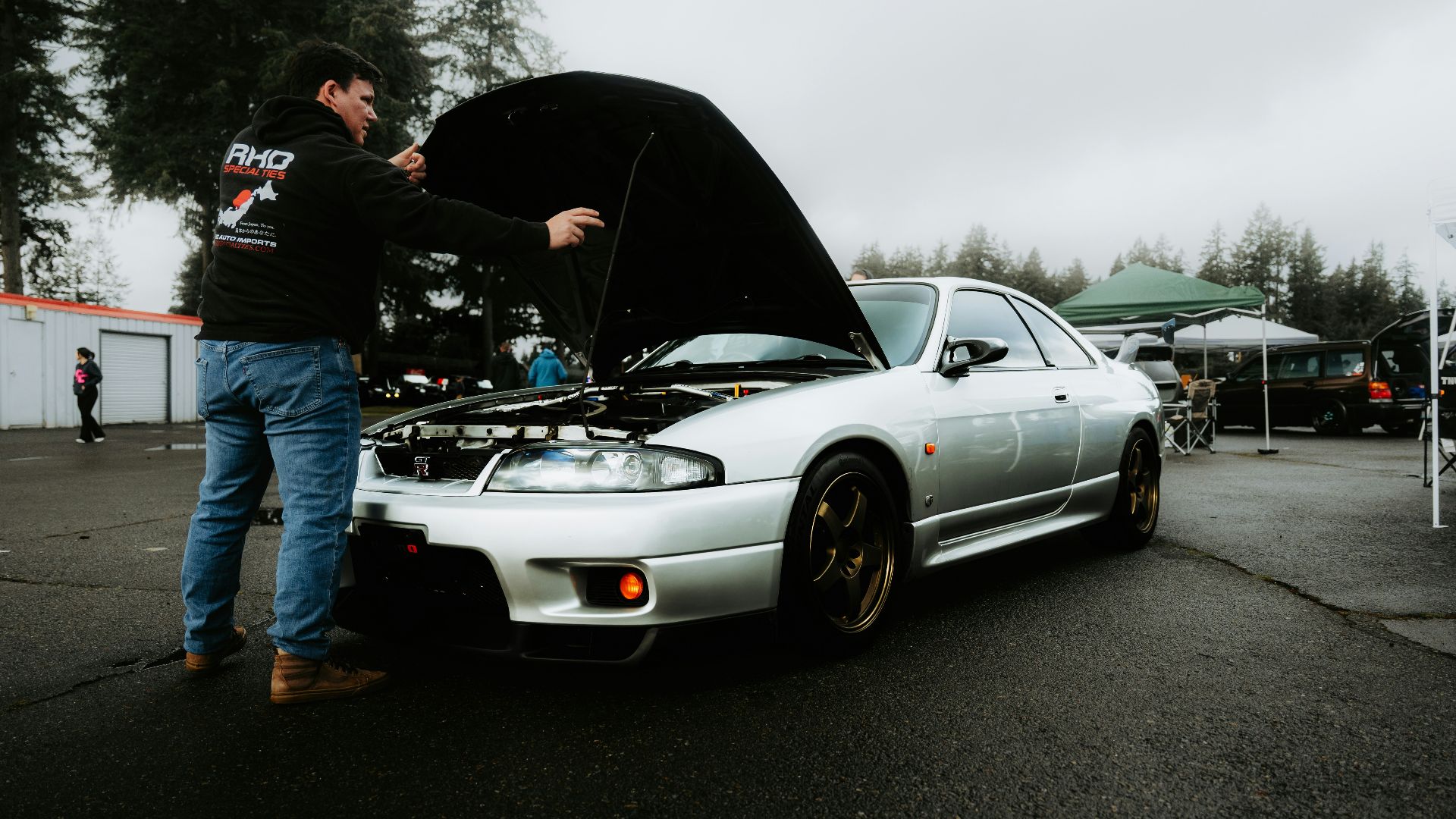 Man inspects car engine with hood open.