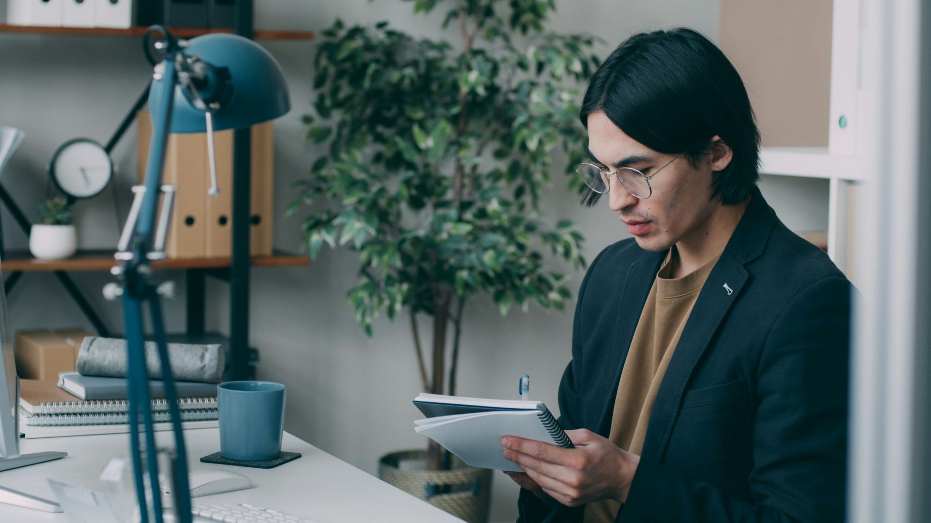 A man standing in front of a desk holding a piece of paper