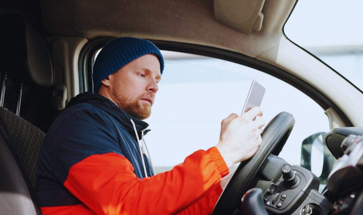 A Bearded Man Using His Smartphone in a Car