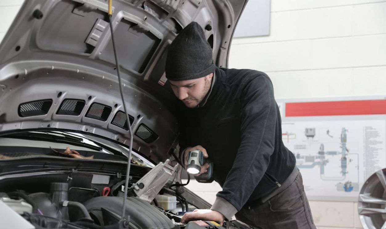 Man in Black Jacket and Black Knit Cap Inspecting Car Engine