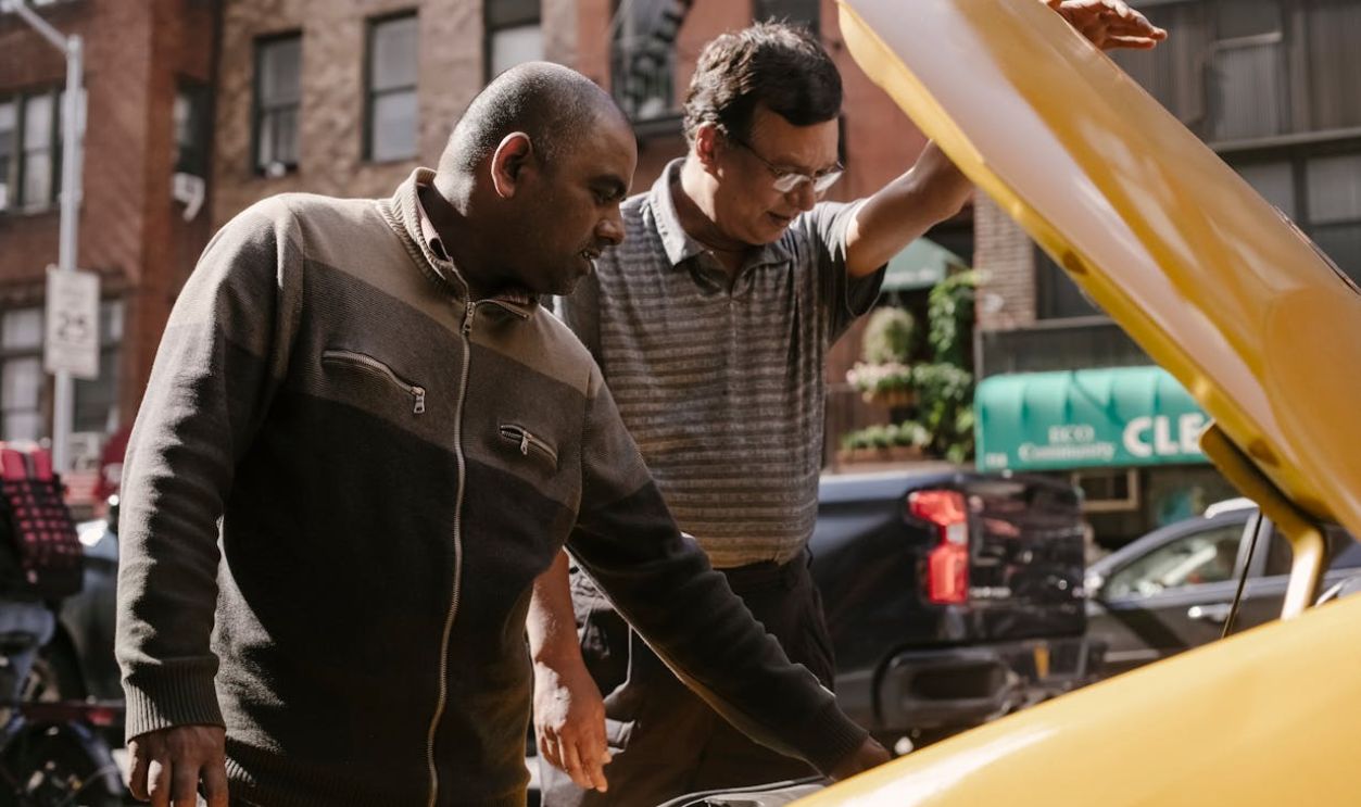 Multiethnic men repairing car on street