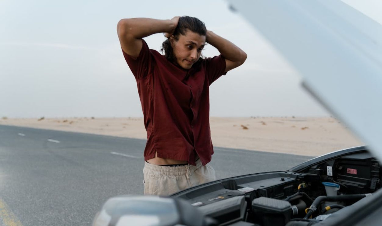 An Upset Man Looking at His Broken Car