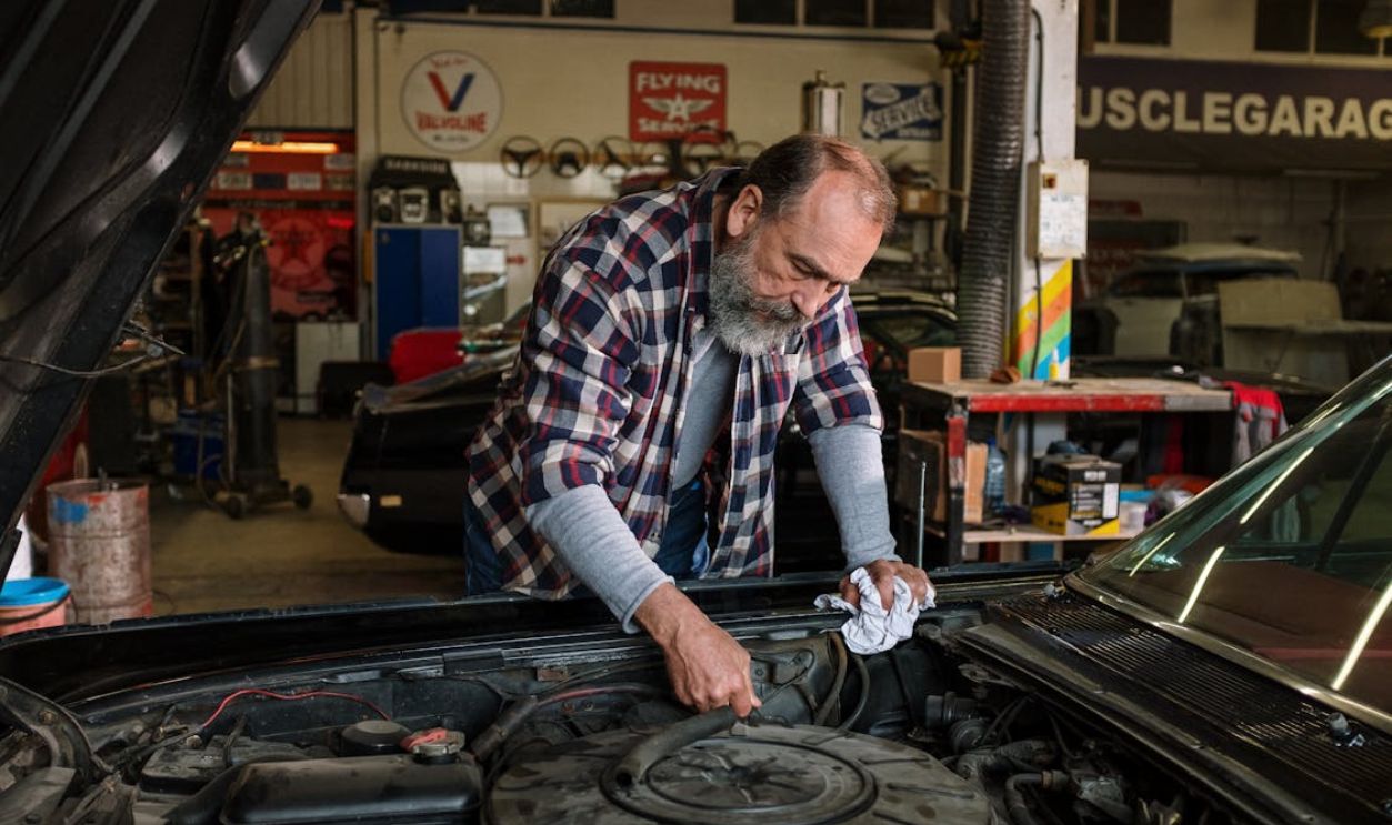 Man in Red White and Black Plaid Dress Shirt Holding Black Car