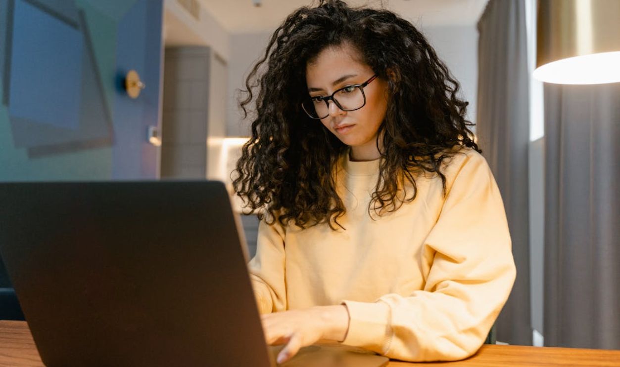 A Woman in Yellow Sweater Working on Her Laptop