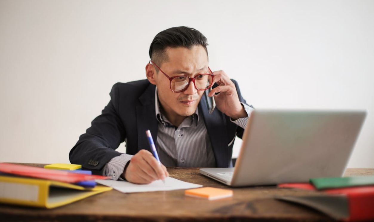 Man in Black Suit Writing On A White Bond Paper