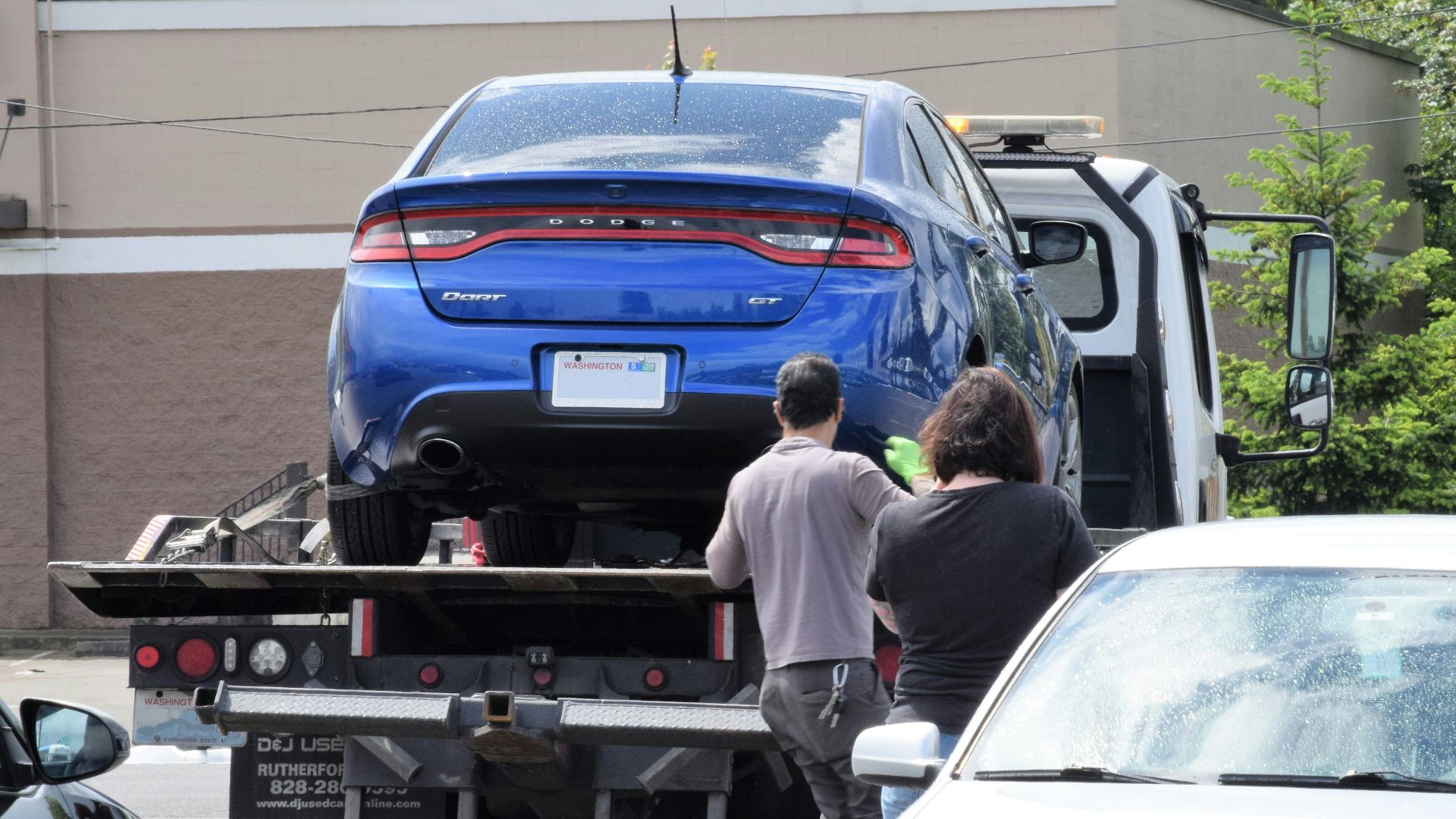 a blue car being loaded onto a flatbed truck