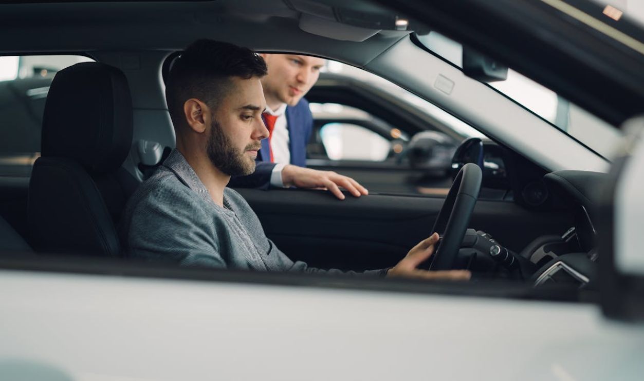 Young Man Exploring Car Interior at Dealership