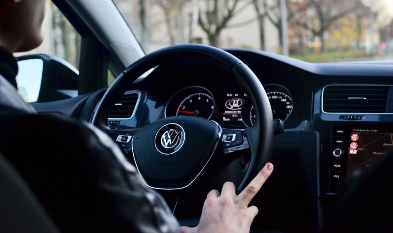 Crop man driving modern vehicle during trip in town