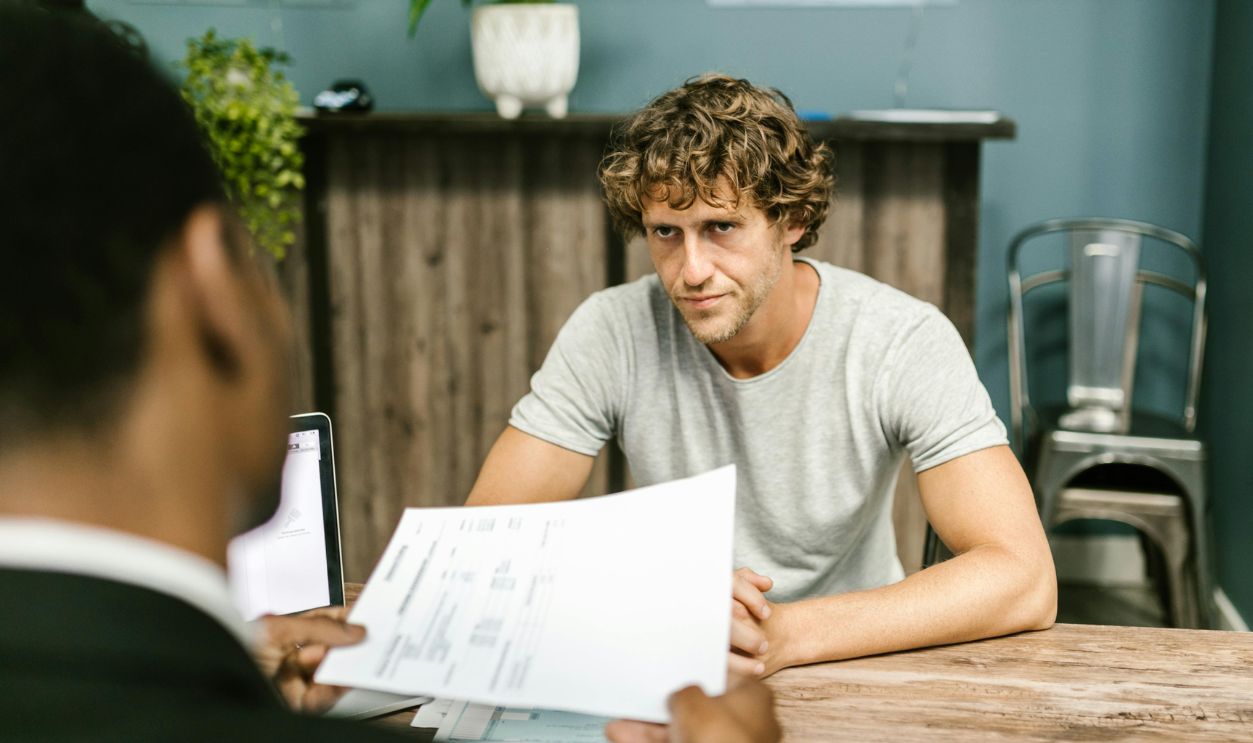 Man in Gray Shirt Sitting by the Table