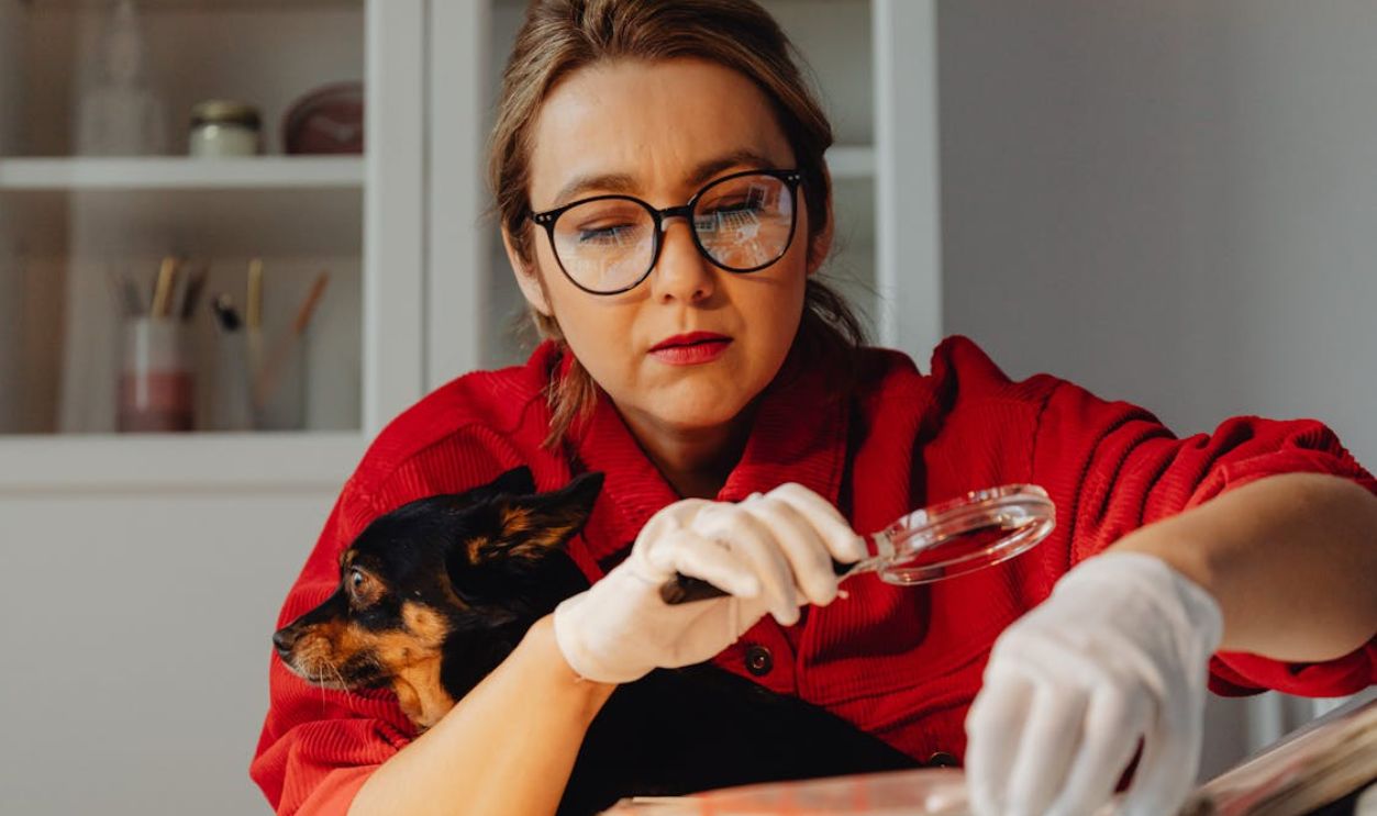 Woman Looking at Old Pictures Through a Magnifying Glass