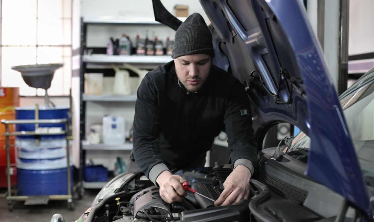 Man in Black Jacket and Black Knit Cap Standing Near Vehicle