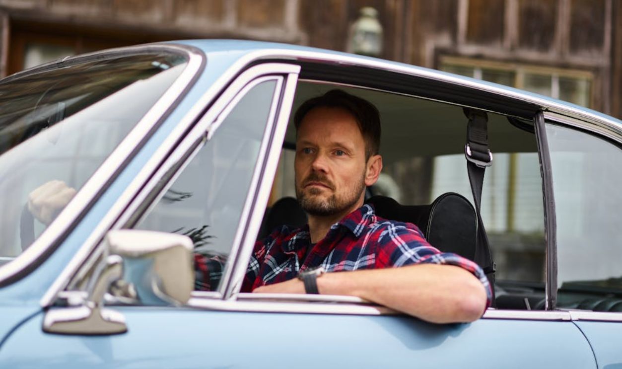 Thoughtful man driving car near old city house